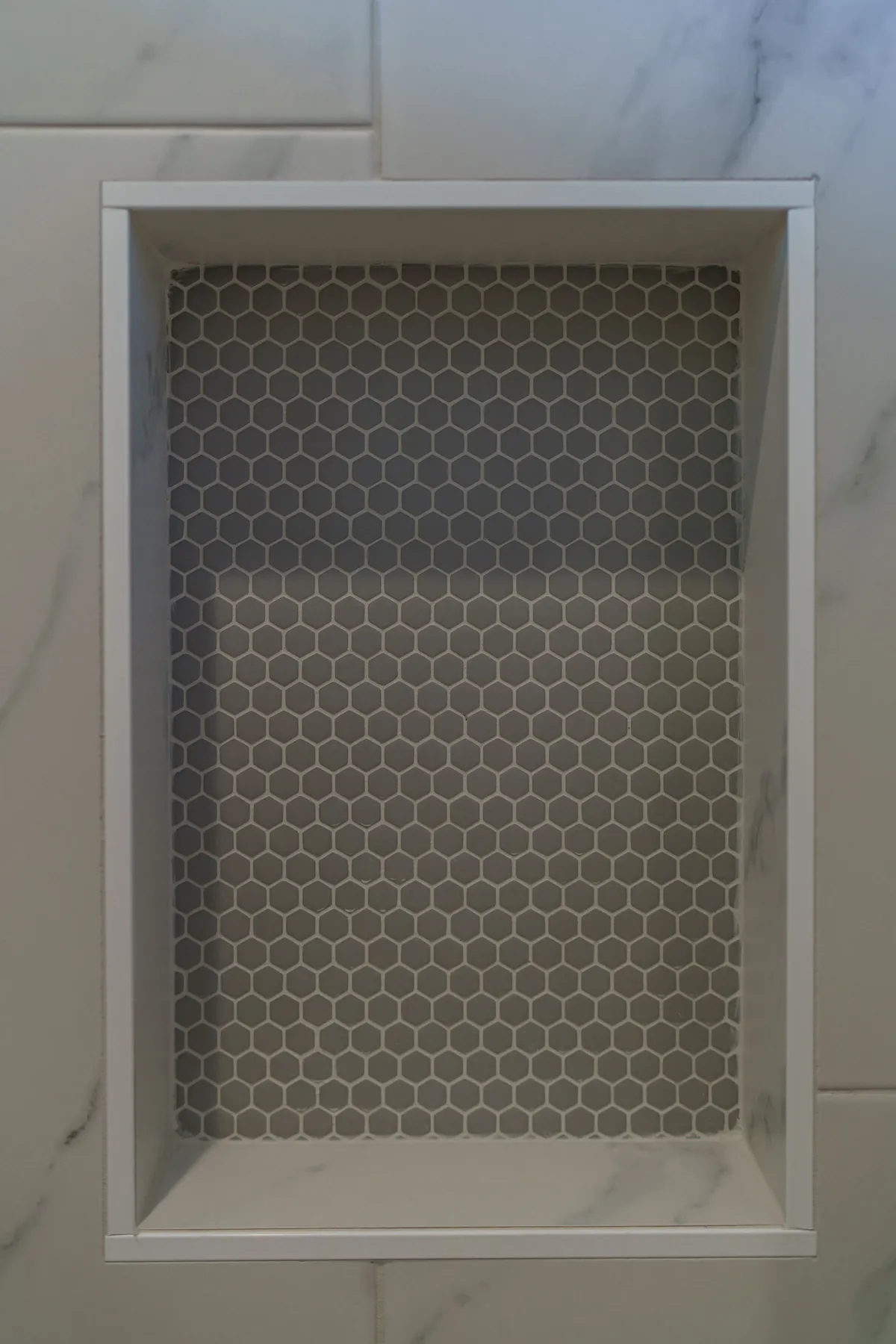 Tiled shower niche: Hex mosaic, framed and set flush with the wall tile.