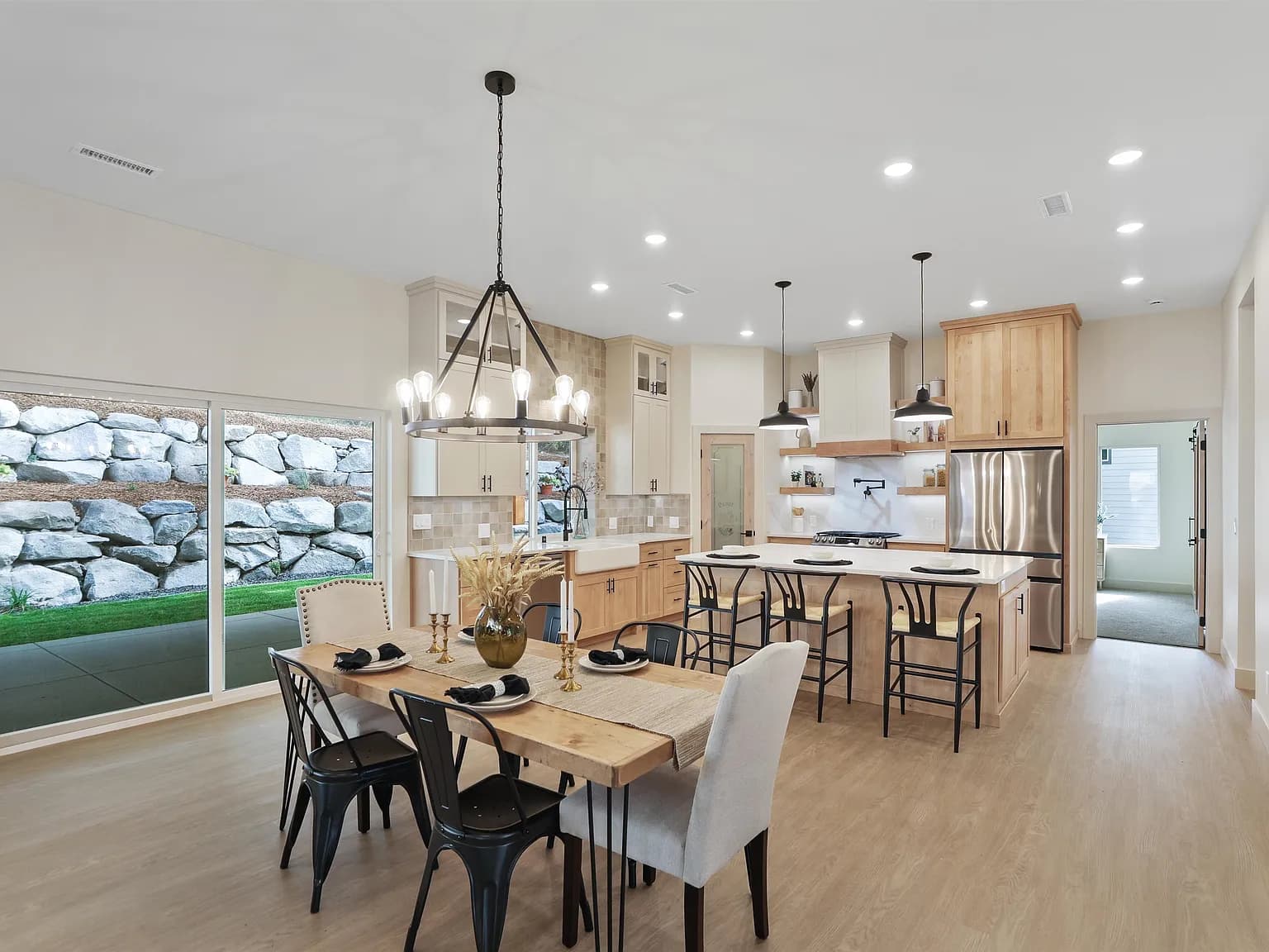Open kitchen and dining room with a maple island and farmhouse sink in a JM Homes build
