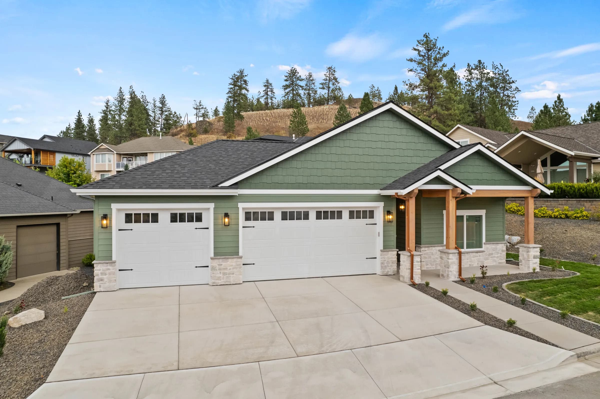 Sage-green craftsman by JM Homes on a neighborhood lot with homes on either side