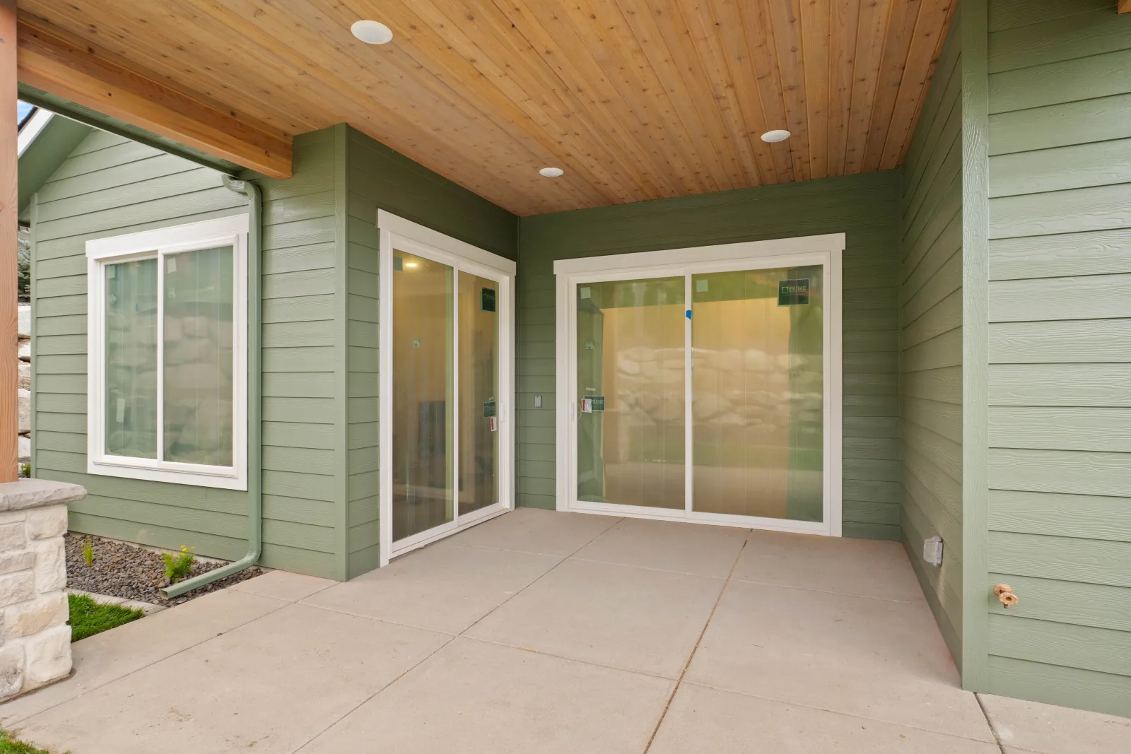 Covered patio with a clear cedar ceiling, timber beam and sliding glass doors