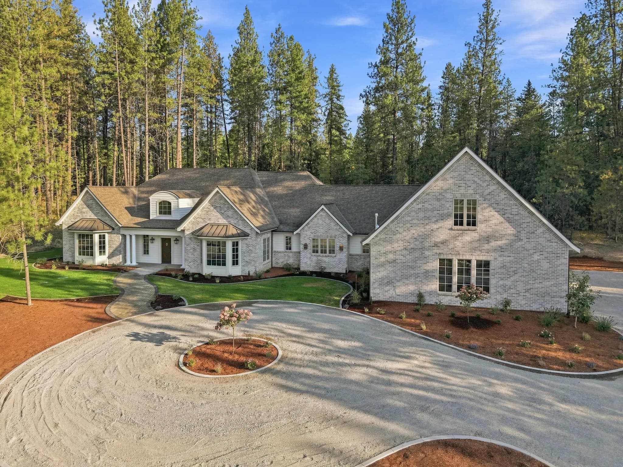 Aerial view of a JM Homes build with a circular gravel drive on a wooded rural lot