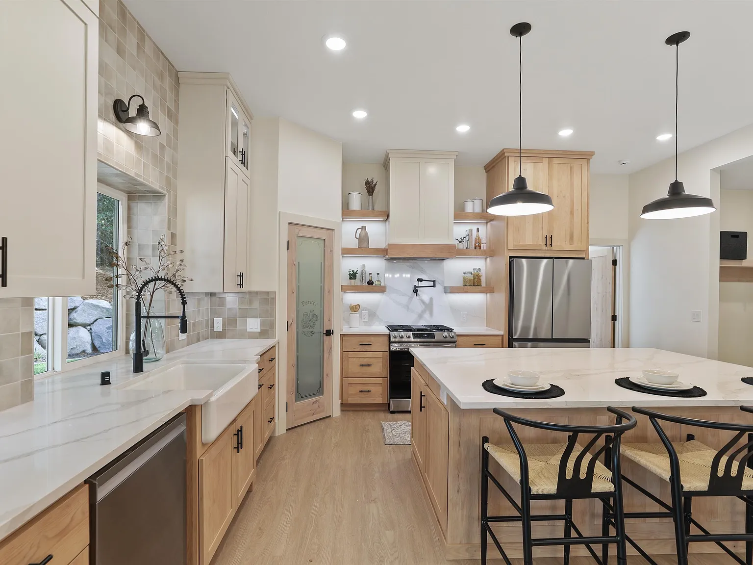 Maple and cream kitchen with a farmhouse sink, marble-look island and black pendant lights